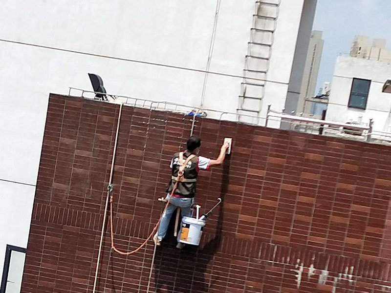 高空外墻防水：外墻面洞和較大裂縫防水密封前用噴水槍等工具將待治理的外墻面、伸縮縫、窗框等部位清理干凈，使施工的外墻面及縫、孔、洞部位達到無油、無塵土、無水泥松散顆粒等雜物。   待其干燥后，將孔、洞、縫用防水密封材料嵌填密實，并達到與原顏色一致，再用快速堵漏靈和透明防水膠膜進行精心施工。整體條形瓷磚外墻面防水，采用高效環保型憎水進行精心施工。該材料具有防水性能優異、透氣性能良好、施工方便、使用安全、質量可靠、耐久性好等特點。