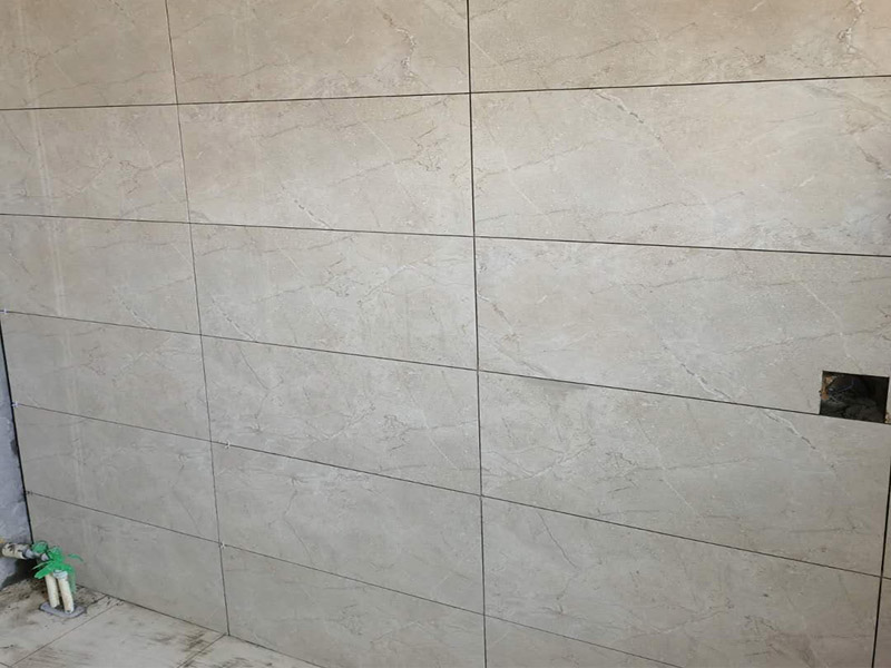 客廳瓷磚鋪貼:鋪貼前，先將所鋪平面表面的塵土、雜物等徹底清掃干凈，平面不能有空鼓、開裂和起砂等現象，如果存在這些現象，要先進行修復處理，在鋪設瓷磚。鋪設地磚施工前，要先在地面彈出十字線，從而控制地磚分隔尺寸。然后要選用1:3干硬性水泥砂漿，砂漿的厚度要在25mm左右。把瓷磚按照要求放在水泥砂漿上，用橡皮錘輕輕敲擊瓷磚的表面，直至瓷磚鋪貼平整。鋪貼完瓷磚后，要進行勾縫處理，先清理干凈瓷磚縫隙里的雜質，再用專用填縫劑進行勾縫處理。