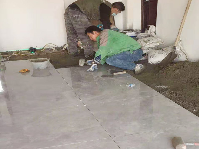 客廳地面貼磚：首先要把基層用水澆濕，除去雜物和浮沙。再抹結合層，需要注意的是要使用1：3的干性水泥漿，按照水平線探鋪平整，然后再把磚放在沙漿上用膠皮錘振實。這時再把地面磚取下澆抹水泥漿，然后把地面磚放實振平就可以了。采用干鋪法可以有效地避免鋪裝過程中造成的空鼓、氣泡等現象發生。但是干鋪法的技術含量比較高，所以費用也會比較貴。
