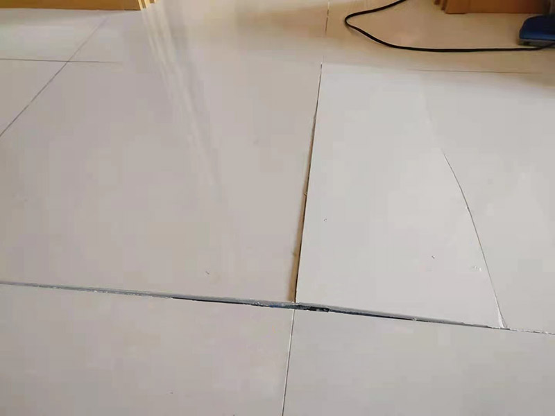 客廳地磚起翹修復：將油灰刀的邊緣滑入松散的瓷磚與其旁邊的瓷磚之間的接縫中。撬起瓷磚并將其移除。用金屬刮刀或小的撬桿的平坦邊緣刮掉基材和瓷磚背面的稀釋劑或瓷磚粘合劑。用相同的工具刮擦周圍空間的舊水泥漿。用清水沖洗除去翹起的瓷磚，然后用濕海綿擦拭，使其干凈。將砂漿抹在缺口邊緣上，然后將稀釋水泥砂漿抹在瓷磚的背面，將瓷磚鋪回原位。如果難以將瓷磚平整，則將瓷磚墊片插入接縫或修補物與包圍它的瓷磚之間的接縫或接縫中。刮掉多余的漿液，并讓該區域靜置約10分鐘。用水蘸軟海綿，然后輕輕擦拭修復區域。瓷磚上出現一層干粉后，請用干抹布擦拭。